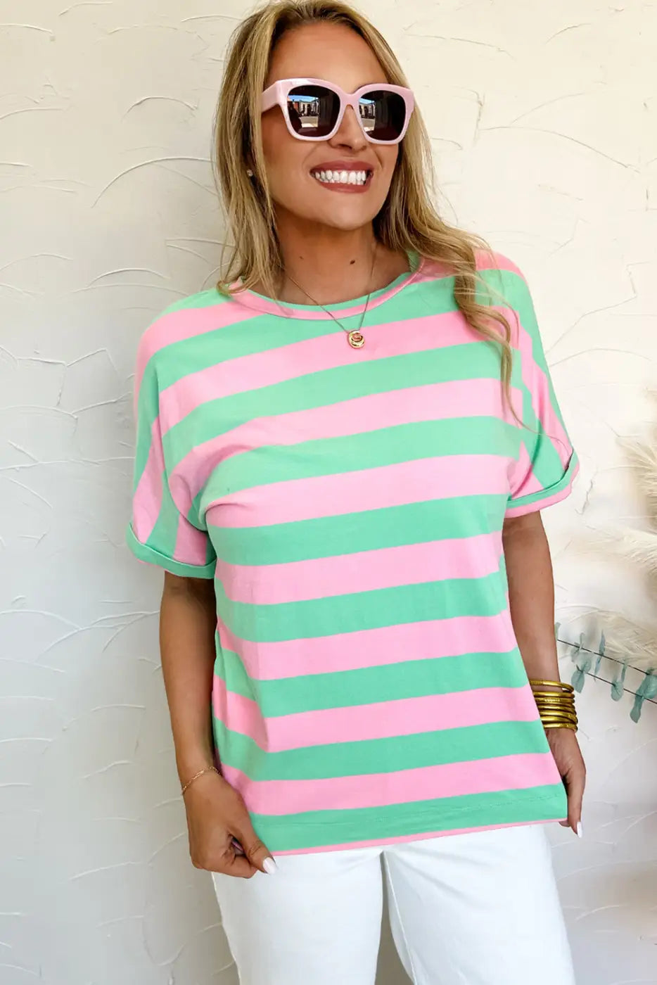 Woman in relaxed elegance tee with pink-green stripes and white sunglasses