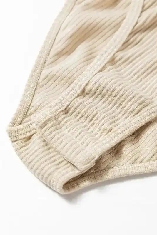Close-up of bottom snap closure on beige Ribbed Balloon Sleeve Bodysuit, emphasizing comfort and secure fit.