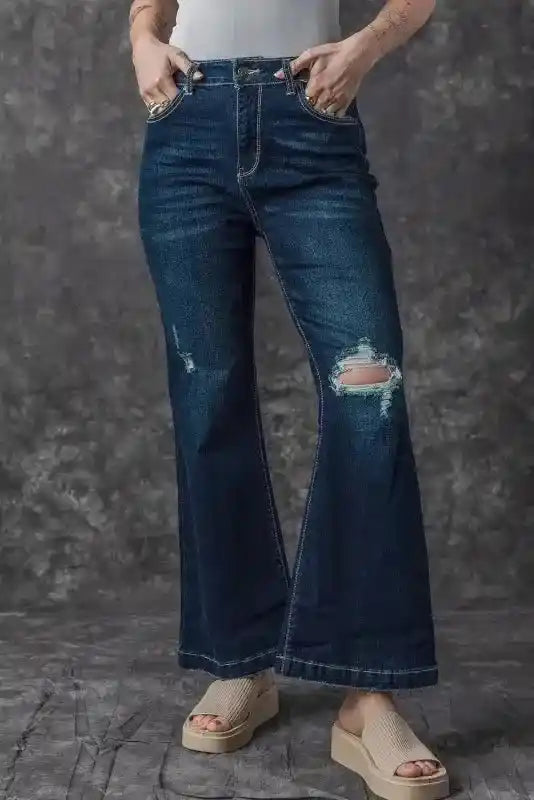 Model in Ripped Bell Bottom Jeans with platform sandals, showing off the casual distressed denim and flared cut.