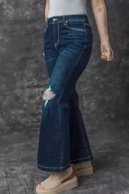 Side angle of Ripped Bell Bottom Jeans on model, emphasizing the ripped knee and wide flare for a bold fashion statement.
