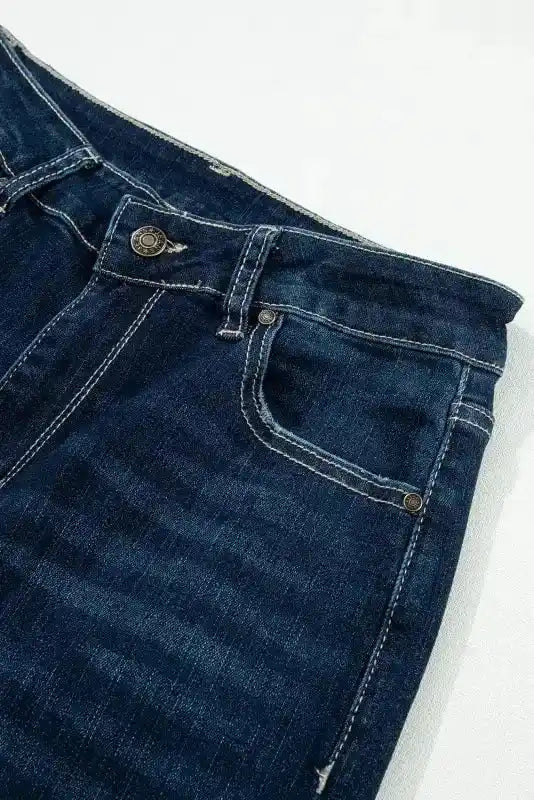 Close-up of waistband and front pocket stitching on Ripped Bell Bottom Jeans, showcasing dark denim and metal button detail.