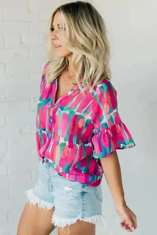 Side profile of Rose Abstract Brushwork Print Blouse paired with denim shorts, highlighting the flowy fabric and ruffle sleeve detail.