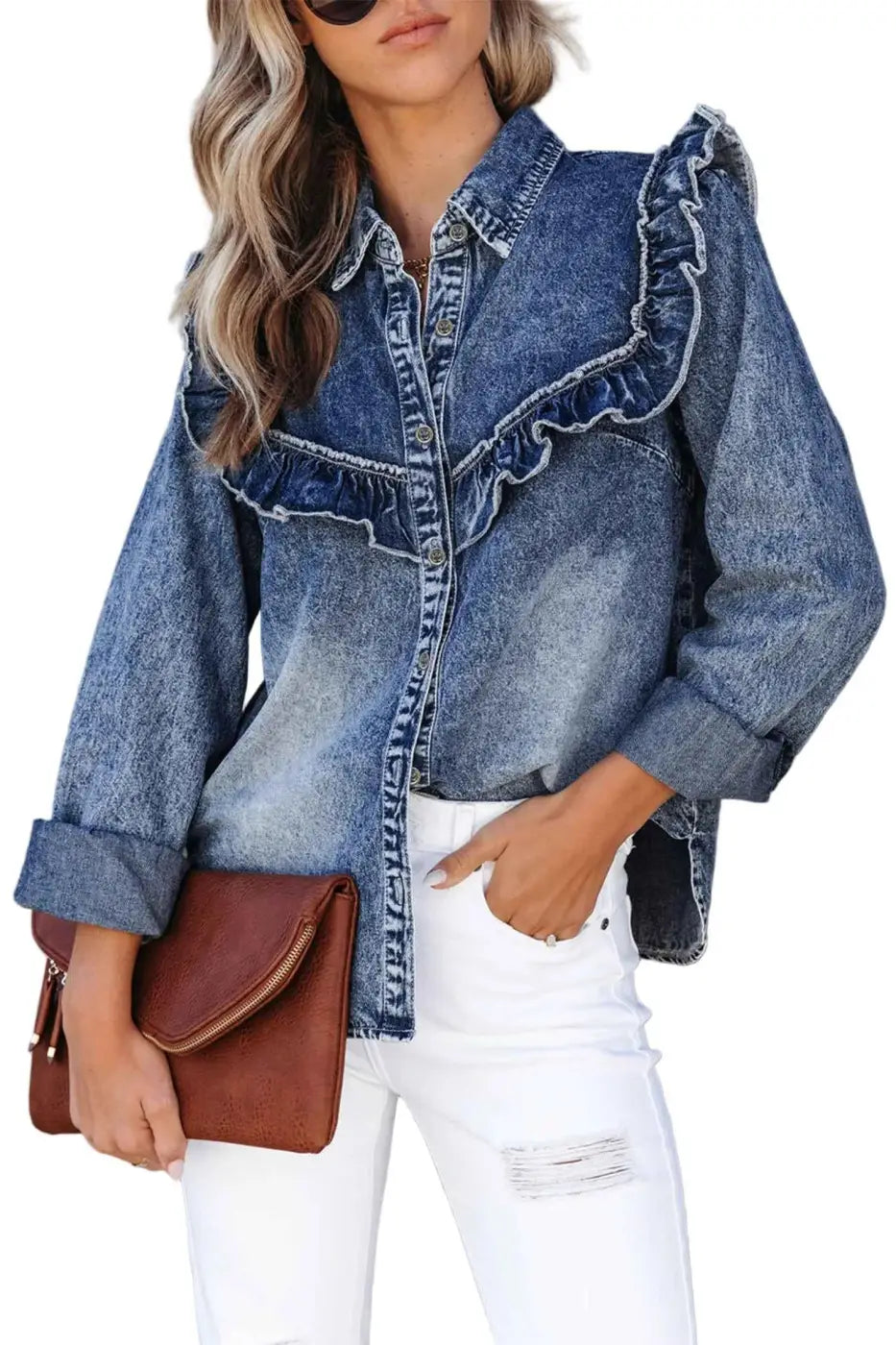 Person wearing a denim jacket with ruffled details and white pants, holding a brown leather bag against a gray background.