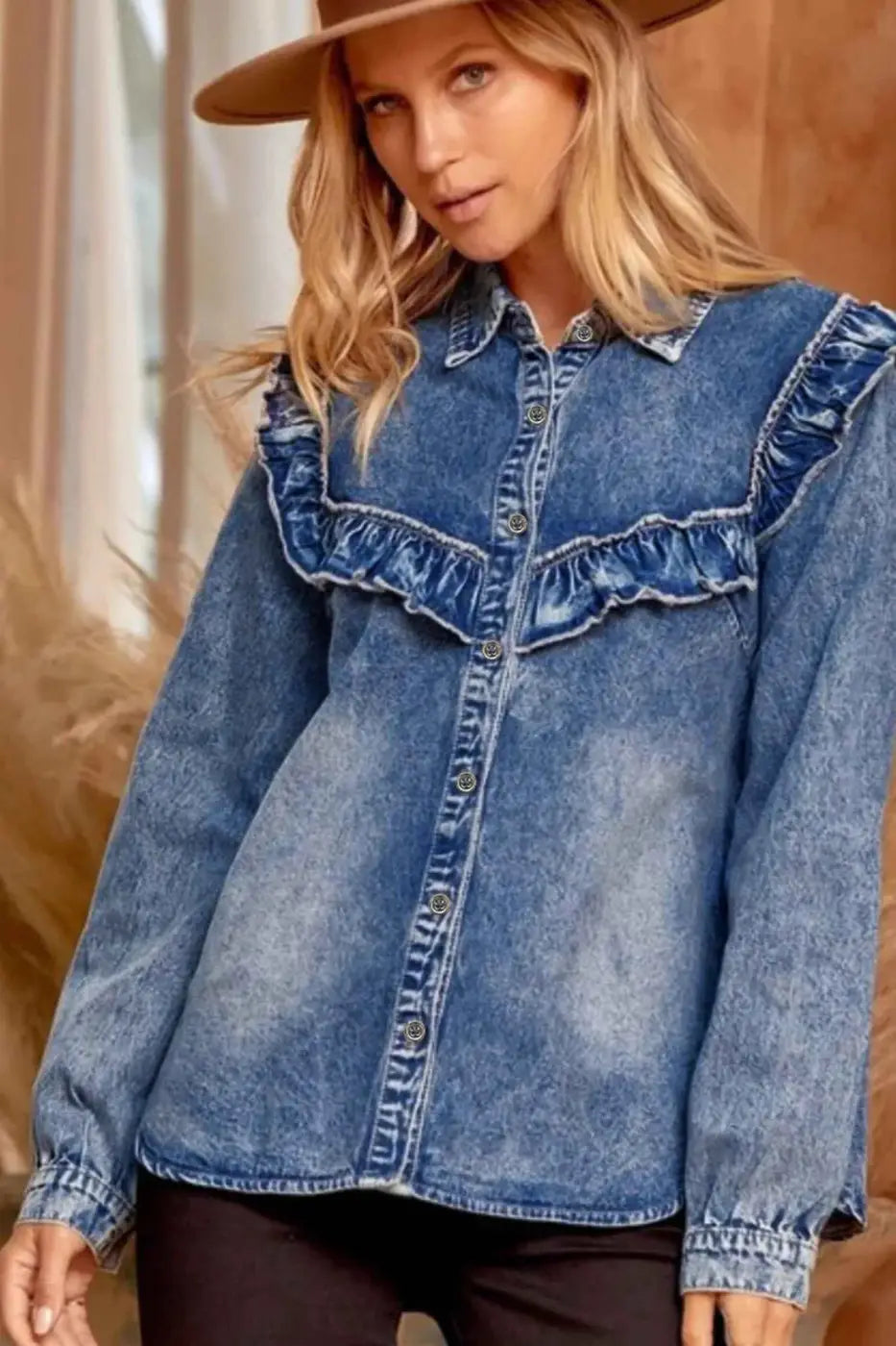 Woman wearing a blue denim shirt with ruffled details against a neutral background