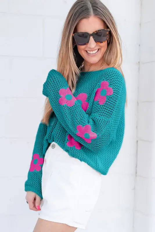 Smiling woman in sunglasses wearing a sea green floral sweater - hollowed knit. Relax relax