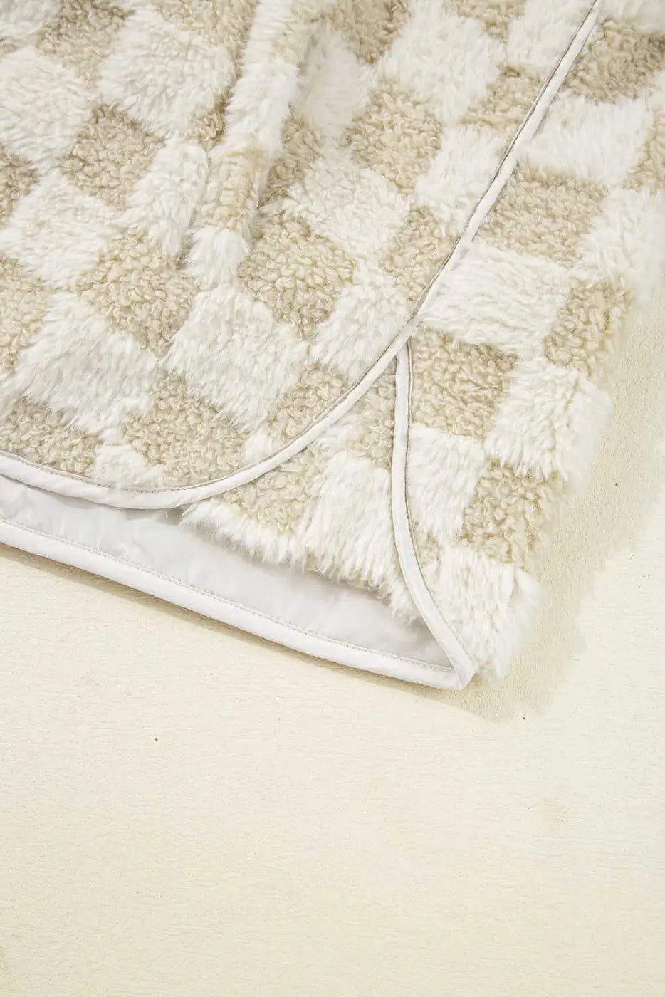 Close-up of a textured Sherpa Fleece Vest with a geometric pattern on a light beige background
