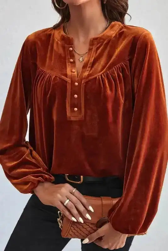 Rust orange version of the Skobeloff velvet blouse styled with black jeans and a brown clutch for a warm, elegant look.