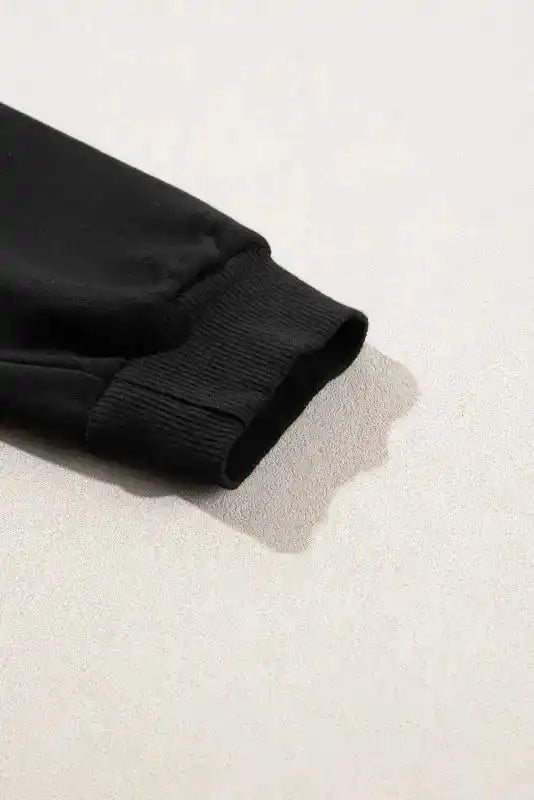 Close-up of ribbed sleeve cuff on Black Snap Button Pullover, highlighting quality stitching and winter-ready comfort.