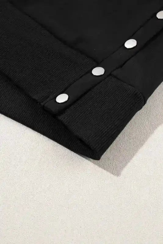 Close-up of side split snap button detail on Black Pullover Sweatshirt, showcasing modern design and casual elegance.