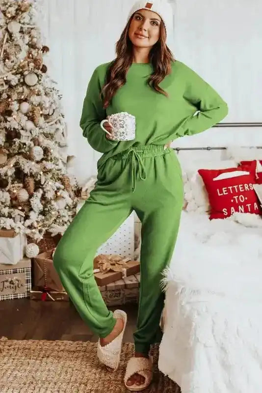 Woman in Spinach Green Jogger Pants Lounge Set holding a mug, showcasing comfy elastic waist joggers and pullover top for casual lounging.