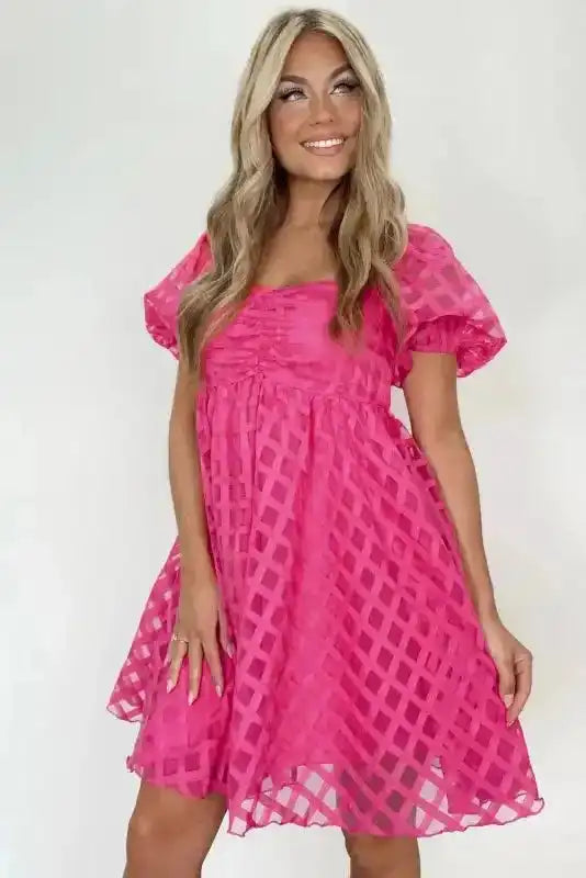 Strawberry pink checkered mini dress with puff sleeves and high waist, styled for feminine summer fashion and special occasions.