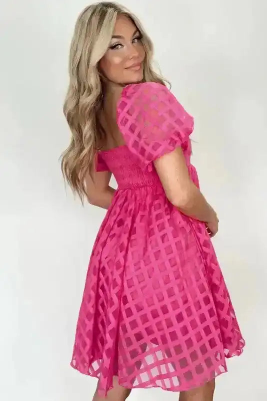 Back view of strawberry pink checkered babydoll dress featuring smocked waist and puff sleeves, ideal for weddings and parties.
