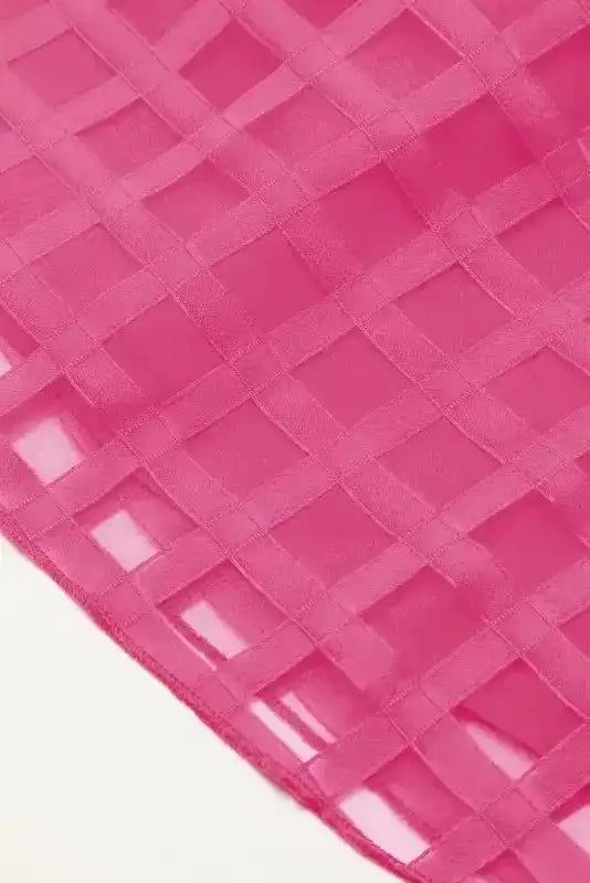Close-up of sheer checkered fabric in strawberry pink, highlighting the lightweight texture and stylish pattern of the babydoll dress.