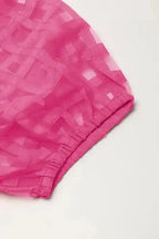 Close-up of puff sleeve with elastic cuff on strawberry pink checkered babydoll dress, emphasizing feminine and airy design.