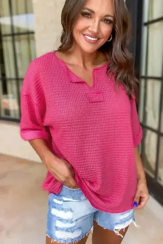 Front view of Strawberry Pink Knit Split‑Neck Top styled with distressed denim shorts, showcasing its split neckline and casual summer vibe.