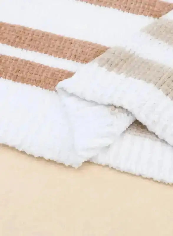 Close-up of sleeve and hem of neutral tone striped sweater, emphasizing ribbed knit texture and quality stitching.