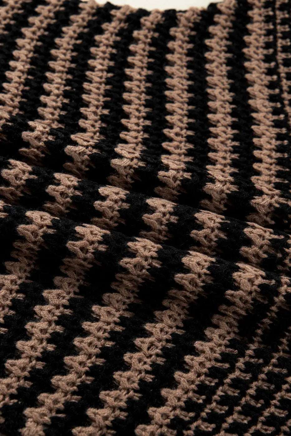 Textured close-up of black and taupe striped knit fabric on slouchy jumper. Lightweight and airy material perfect for everyday wear.