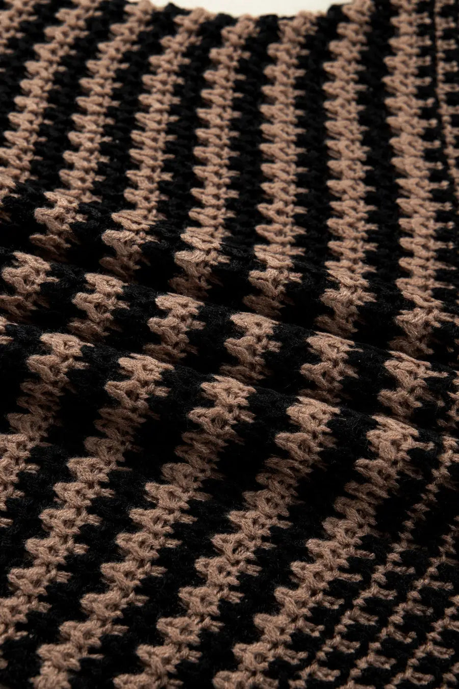 Textured close-up of black and taupe striped knit fabric on slouchy jumper. Lightweight and airy material perfect for everyday wear.