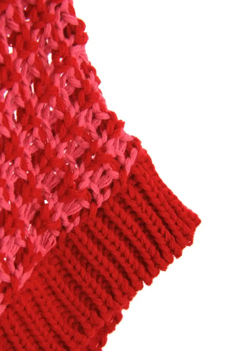 Close-up of red and pink striped knit texture and ribbed hem of slouchy jumper. Soft, breathable fabric ideal for warm weather.
