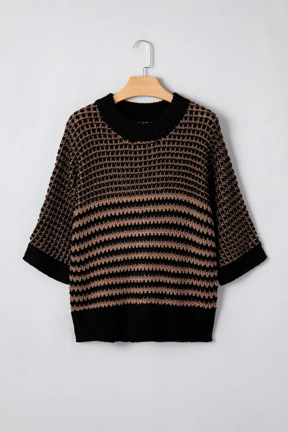 Front view of black and taupe striped soft-knit slouchy jumper on hanger. Short sleeve sweater with ribbed collar and relaxed silhouette.