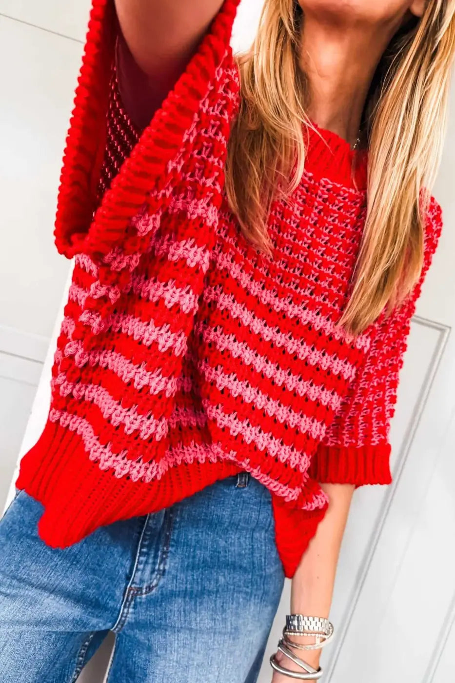 Vibrant red and pink striped slouchy jumper in soft knit, styled with jeans. A bold and breathable short sleeve sweater for daily wear.