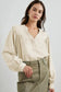 Woman in stylish notched v-neck blouse with puffed sleeves and olive green cargo pants