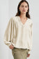 Cream-colored stylish notched v-neck blouse with voluminous sleeves