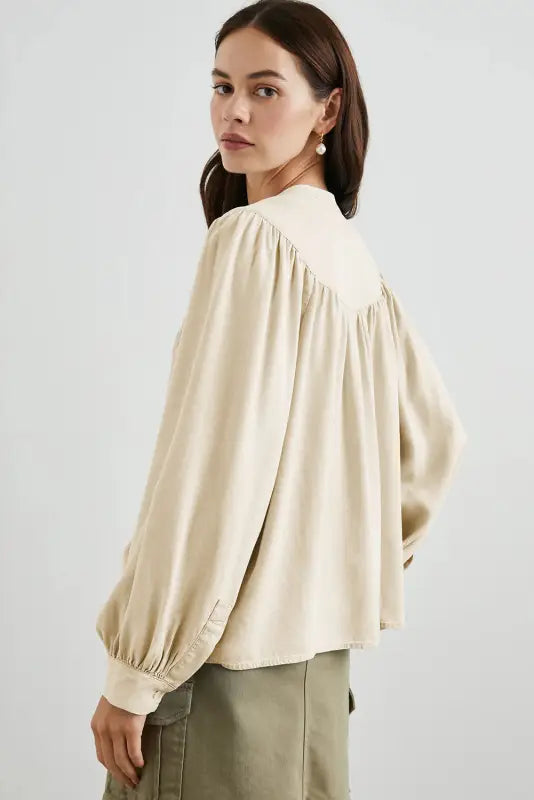 Stylish notched v-neck cream-colored blouse with gathered shoulders and billowy sleeves