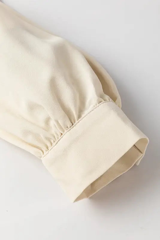 Cream-colored fabric sleeve with elasticated cuff on stylish notched v-neck blouse