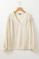 Stylish notched v-neck blouse: cream long-sleeved with gathered shoulders on wooden hanger