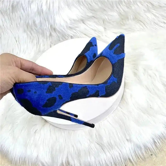 Close-up of Blue‑Black Graffiti Suede Heels held in hand, highlighting suede texture and pointed toe. Trendy court shoes for women.