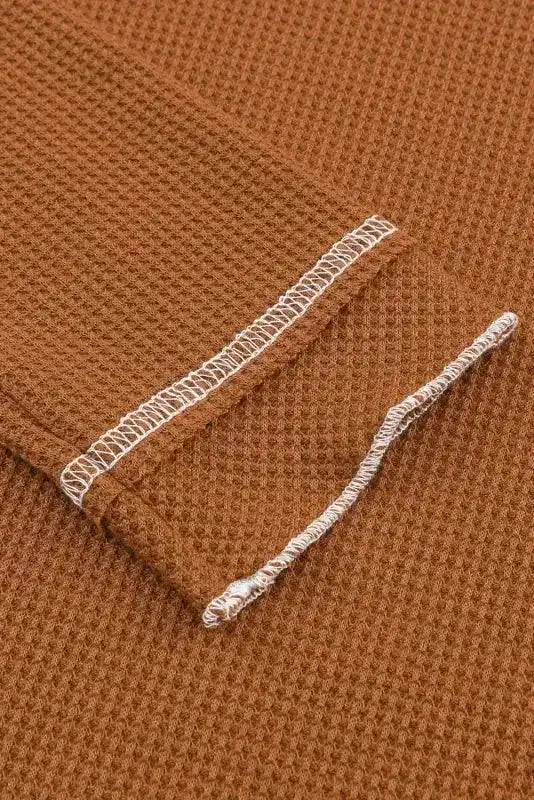 Detailed view of brown waffle knit sleeve with raw edge seam, emphasizing the top's cozy and stylish texture.