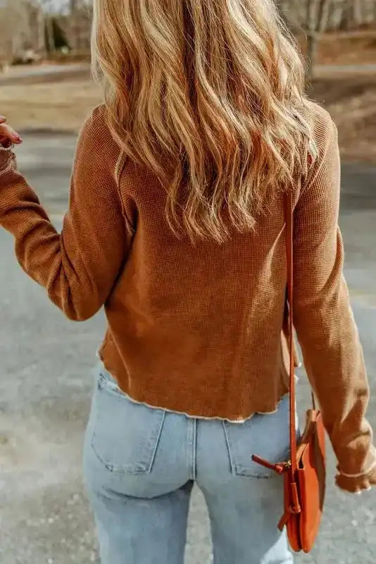 Back view of brown waffle knit long sleeve top with raw hem, highlighting its relaxed fit and casual design.