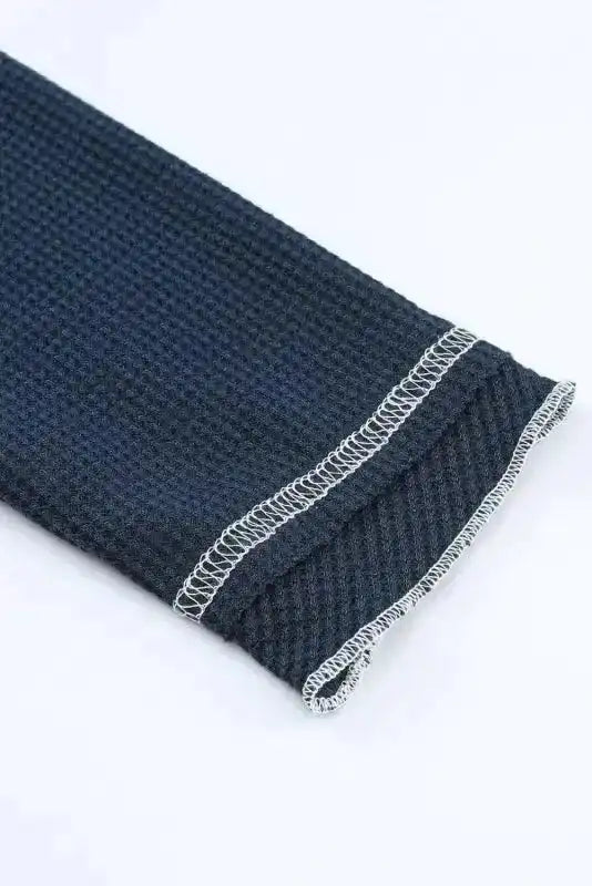 Close-up of sleeve hem on navy blue Round Neck Textured Top, featuring contrast stitching and soft textured knit fabric.