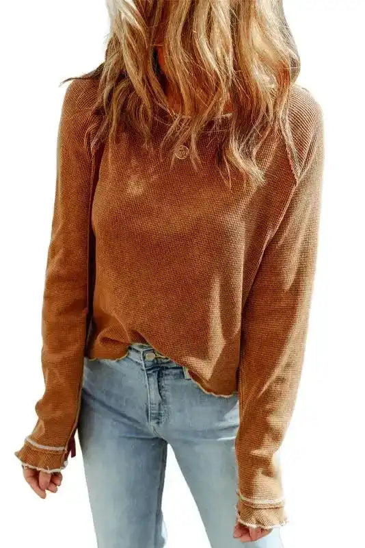 Studio shot of brown textured long sleeve top with raw hem, showcasing its casual and versatile design.