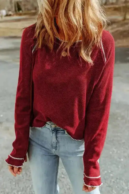 Model wearing red Round Neck Textured Top with long sleeves and contrast seams, styled with jeans for a casual chic look.