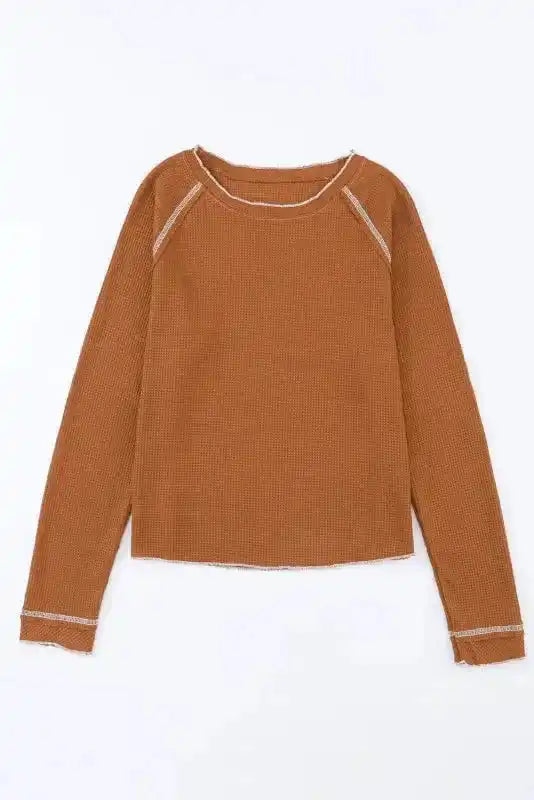 Flat lay of brown waffle knit long sleeve top with round neck and raw edge seams, perfect for cozy seasonal outfits.