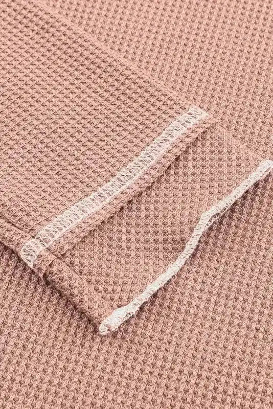 Close-up of apricot pink waffle knit fabric sleeve with raw edge detailing, highlighting the textured material.