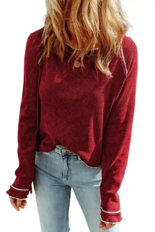 Round Neck Textured Top in red with long sleeves, styled casually with jeans for a cozy fall look. Features contrast stitching and waffle knit fabric.