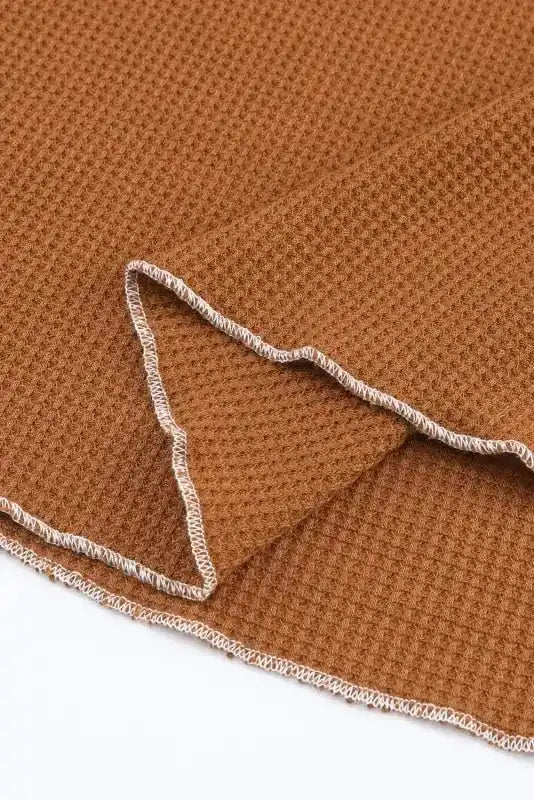 Close-up of brown textured hem with raw edge finish, showcasing the soft waffle knit fabric and casual design.