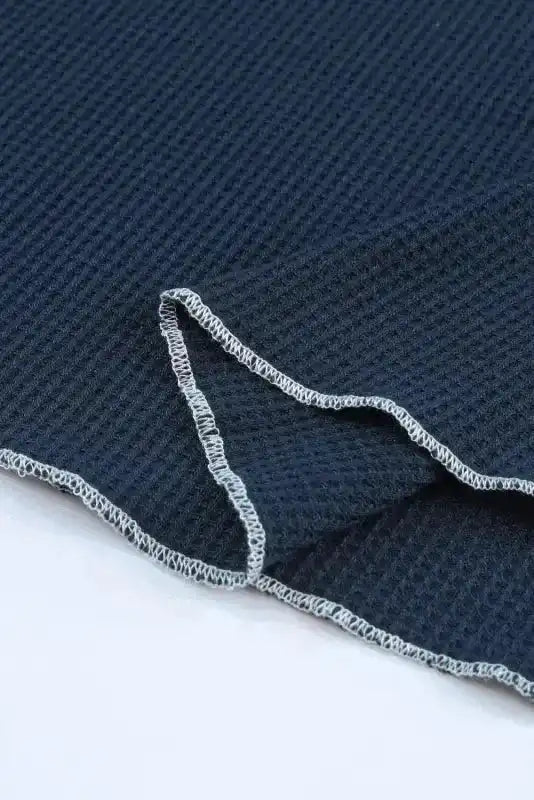Detailed view of hem on navy blue Round Neck Textured Top, showing raw edge finish and waffle knit texture for casual appeal.