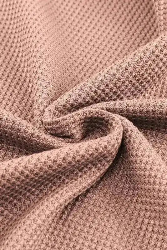 Macro shot of apricot pink waffle knit fabric, showcasing the breathable and cozy texture of the long sleeve top.