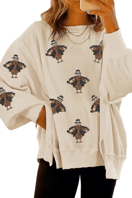Beige sweater with turkey pattern worn by a person, blurred background