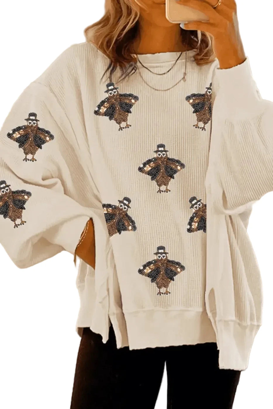 Beige sweater with turkey pattern worn by a person, blurred background