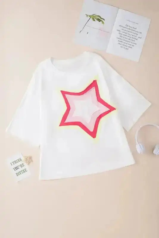 Flat lay of white oversized T-shirt with multicolor star patch. Half sleeve top ideal for casual UK outfits and everyday comfort.