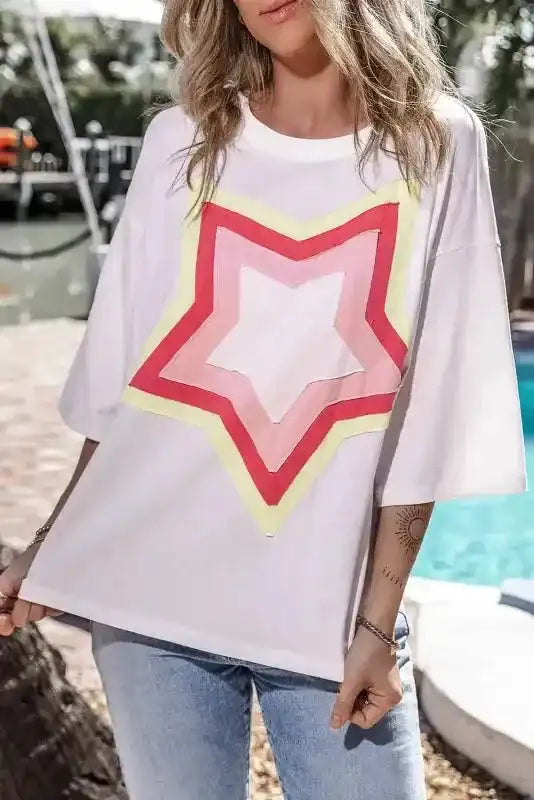 Front view of white oversized T-shirt featuring colorful layered star patch. Half sleeve design perfect for relaxed UK fashion styling.