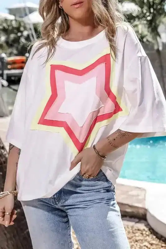 White oversized T-shirt with bold red, pink, and yellow star patch on front. Half sleeves and relaxed fit for casual UK streetwear style.