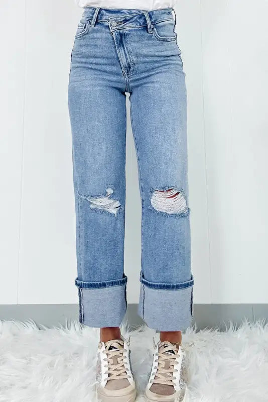 Urban edge asymmetrix light blue distressed jeans with ripped knees and folded cuffs