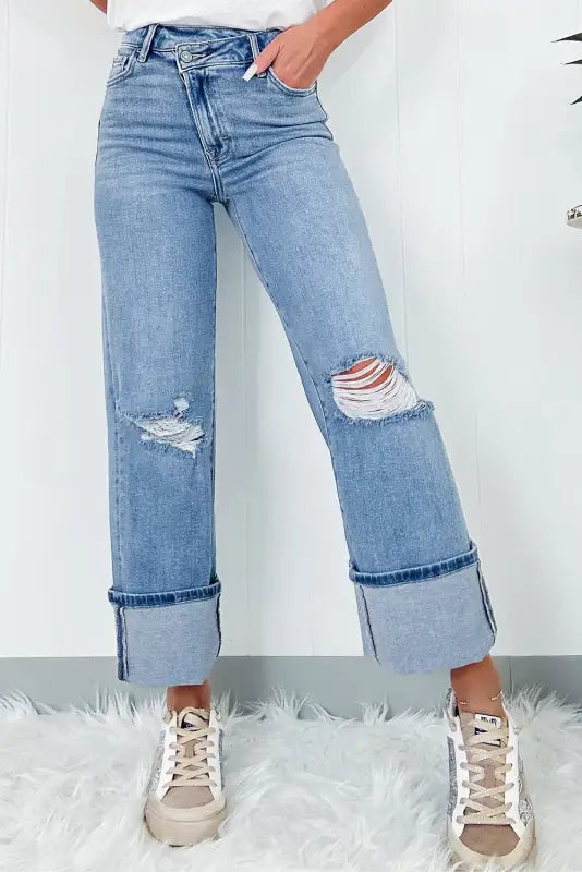 Urban edge asymmetrix light blue distressed jeans with wide cuffed legs and knee rips