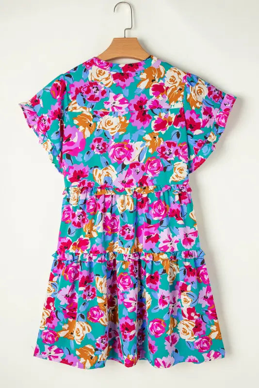 Verde flora dress: colorful floral print with short sleeves and tiered skirt on wooden hanger